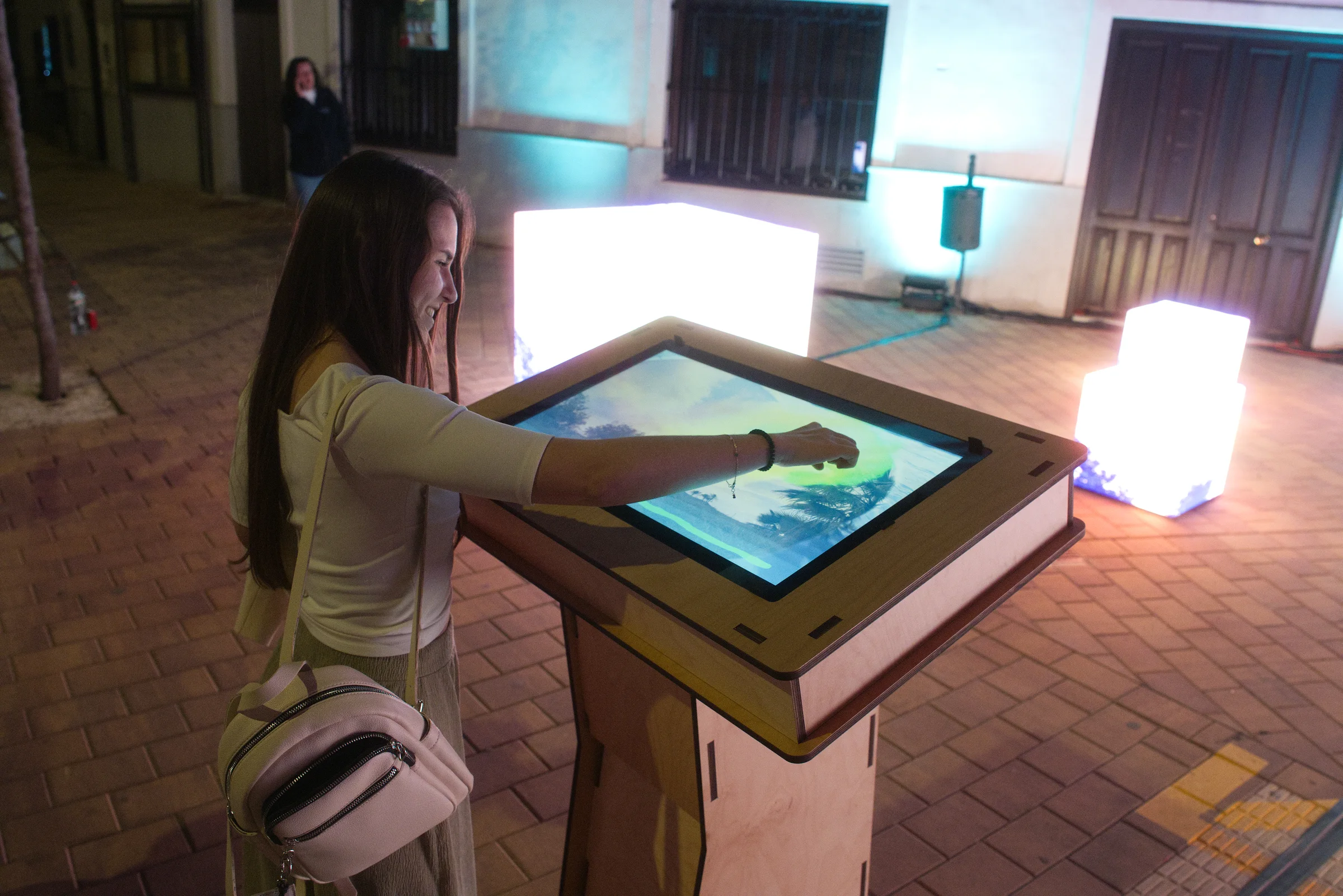 Visitor interacting with a tactile audiovisual installation surrounded by illuminated cubes