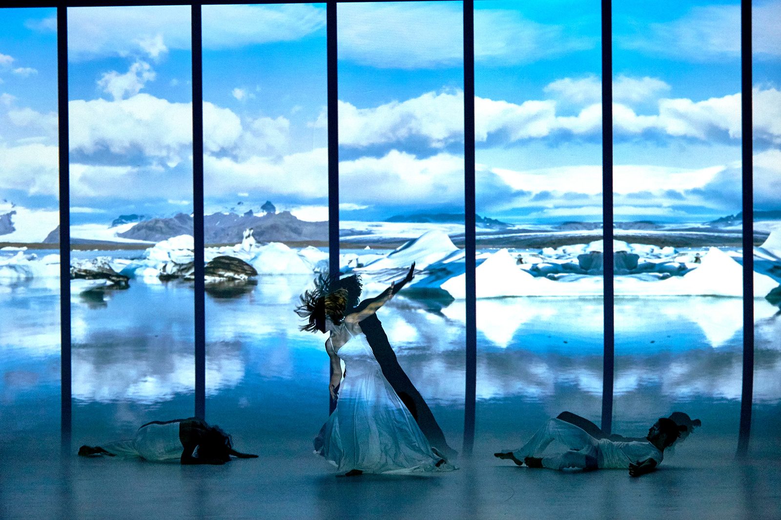 Four performers crossing an illuminated glacial landscape