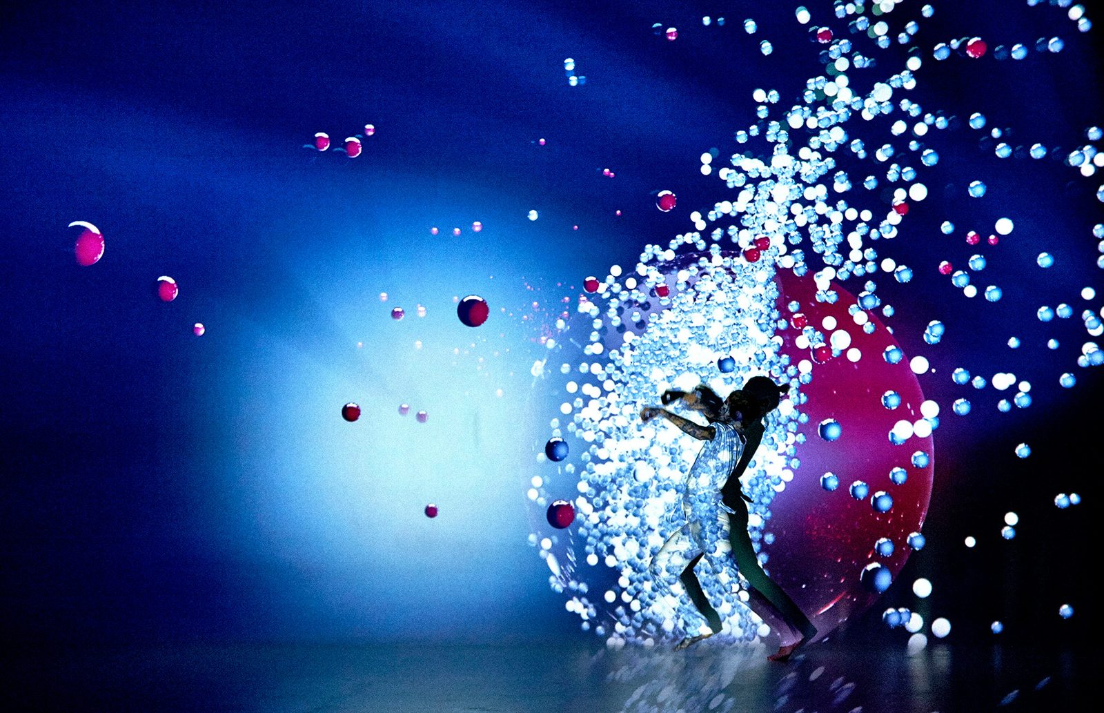 A dancer moving through projected blue and red particles