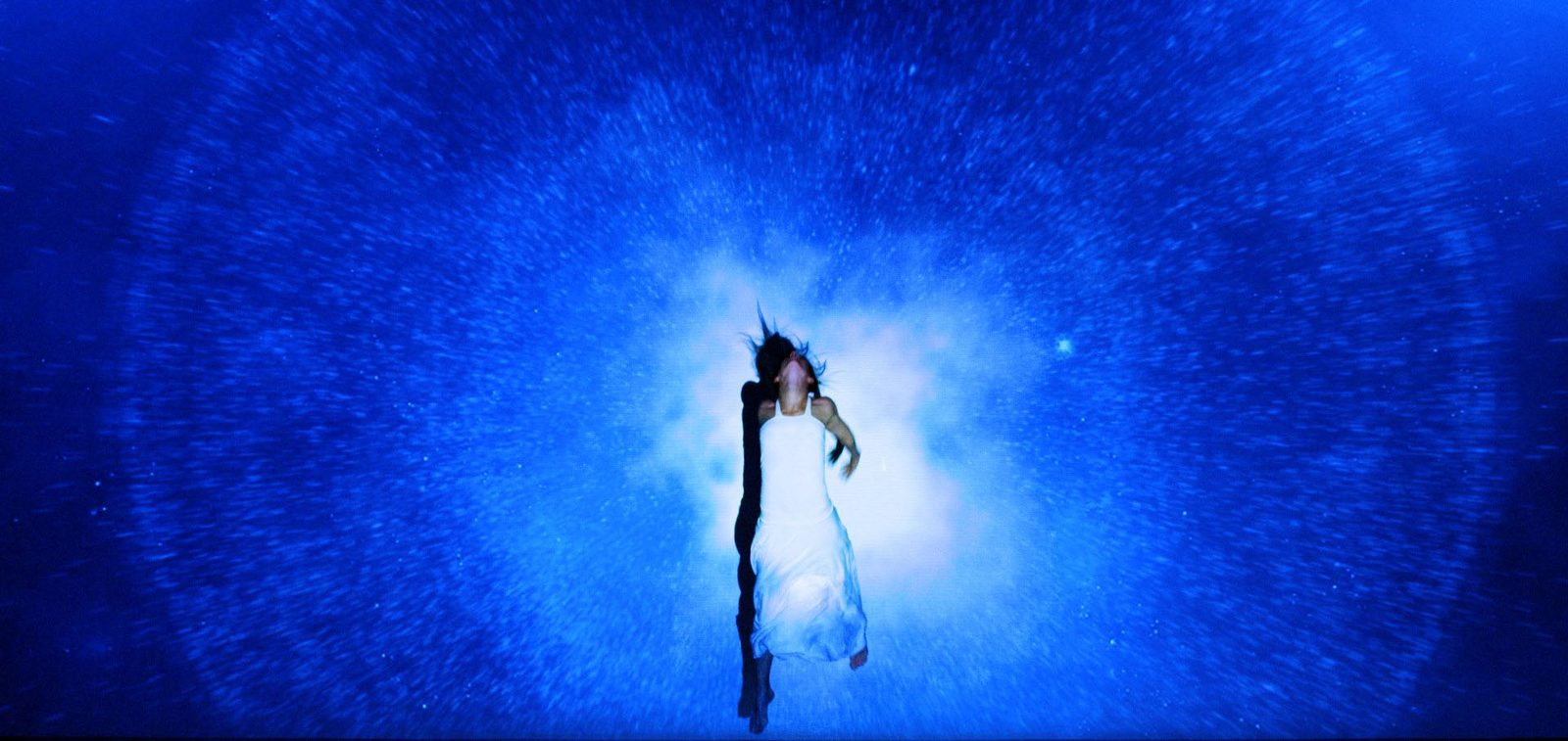 A performer emerging from a radiating blue image